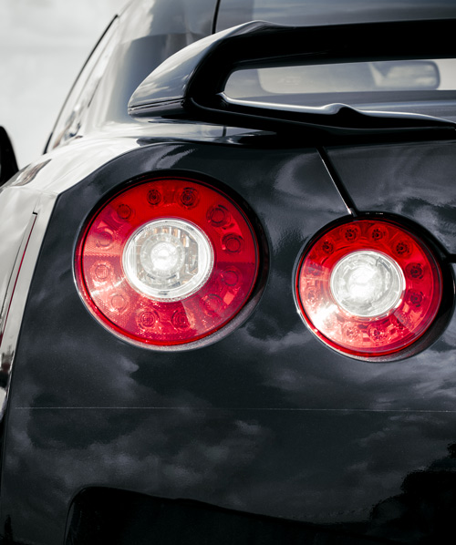 rear view of a black sports car showcasing round red taillights and sleek aerodynamics performance vehicle design