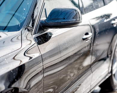 black car side view with water droplets reflecting a clean surface showcasing detailing and shine near seven times refreshment