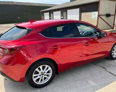 red hatchback car parked in front of building featuring three door configuration and stylish design